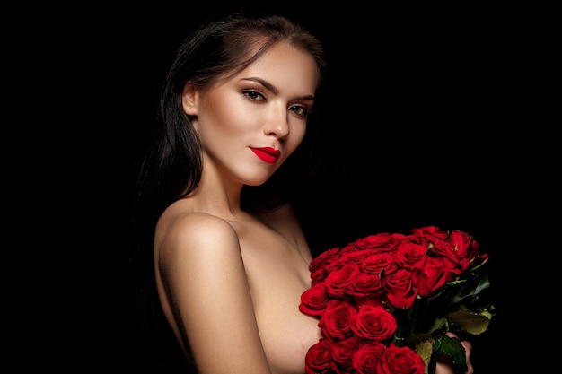 Belle femme séduisante tenant un grand bouquet de roses rouges