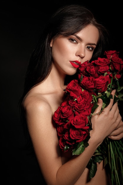 Belle femme séduisante tenant un grand bouquet de roses rouges