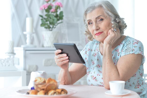 Belle femme senior à l'aide d'une tablette moderne