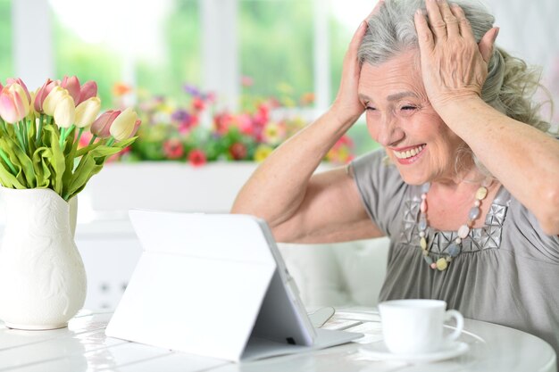 Belle femme senior à l'aide d'une tablette moderne