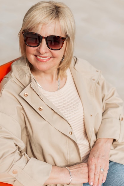 Belle femme senior blonde à la mode avec des lunettes de soleil dans des vêtements élégants à la mode par une chaude journée de printemps