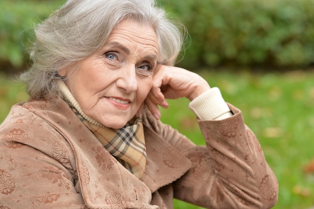 Belle femme senior avec feuille posant à l'extérieur