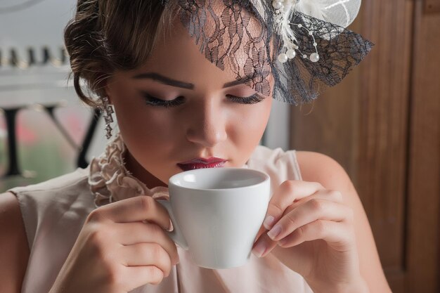 Belle femme sensuelle aux longs cheveux noirs en luxueuse robe à paillettes posant dans un café d'été