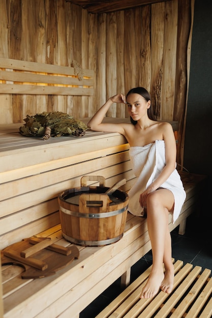 Belle femme en serviette blanche relaxante dans un sauna