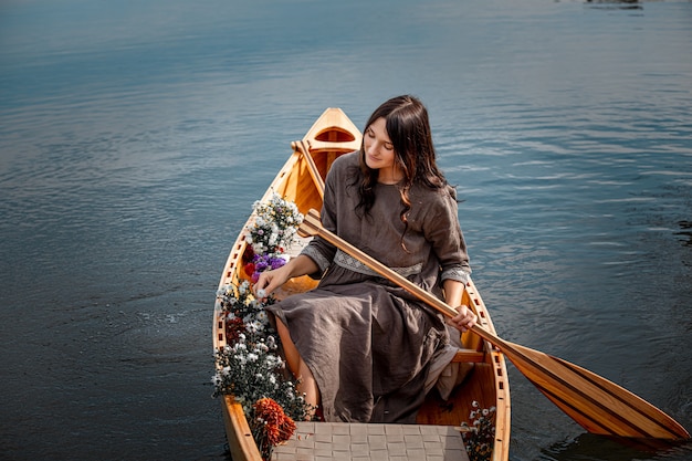 Belle femme seule dans un bateau en bois flottant sur l'intimité du lac avec la nature