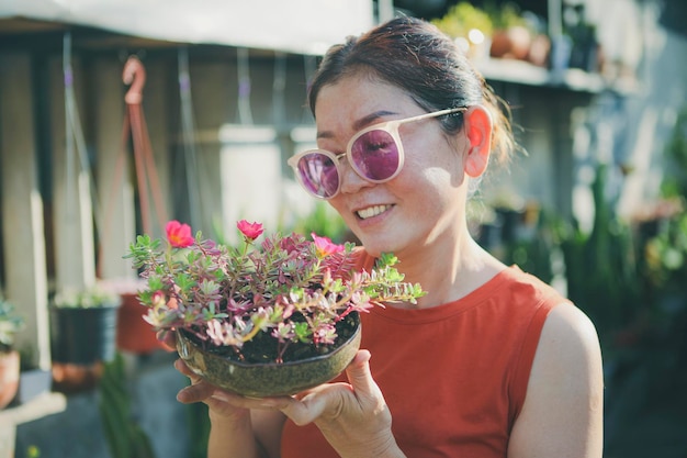 Belle femme soulevant le pot de fleur de floraison avec le visage de bonheur