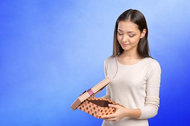 Belle femme souriante aux cheveux longs, tenant une boîte-cadeau