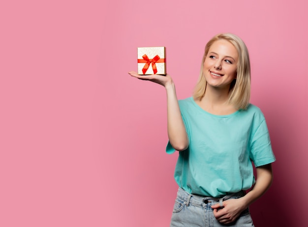 Belle femme souriante avec boîte-cadeau sur mur rose