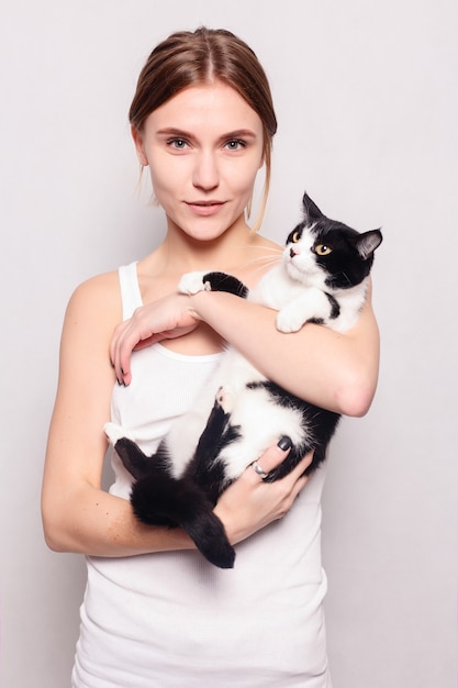 Belle femme souriante avec un chaton dans ses bras, photo studio, gros plan