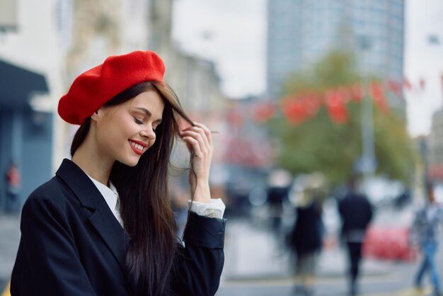 Photo une belle femme souriante avec des dents se promène dans la ville sur la toile de fond des immeubles de bureaux élégants vêtements vintage à la mode et maquillage voyage de promenade d'automne