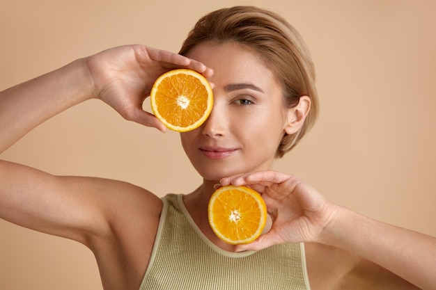 Belle femme souriante avec des fruits à l'orange Vitamine recommandée par la femme pour la peau