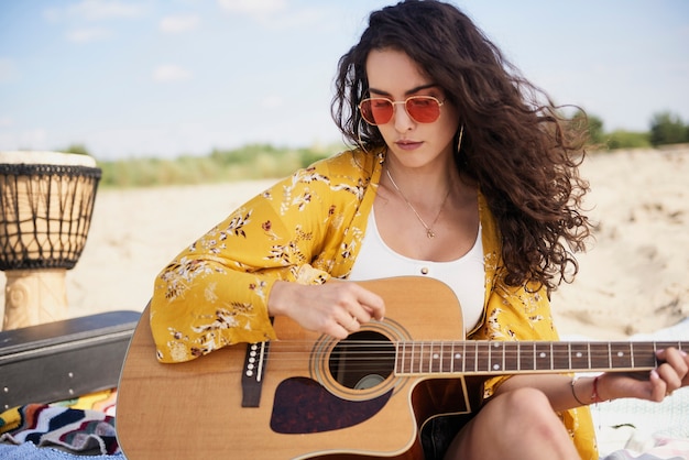 Belle femme souriante jouant de la guitare sur la plage