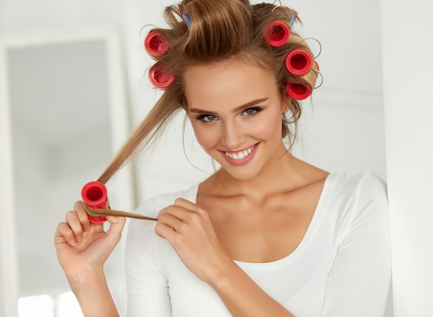 Belle femme souriante, lissage de longs cheveux blonds en bonne santé