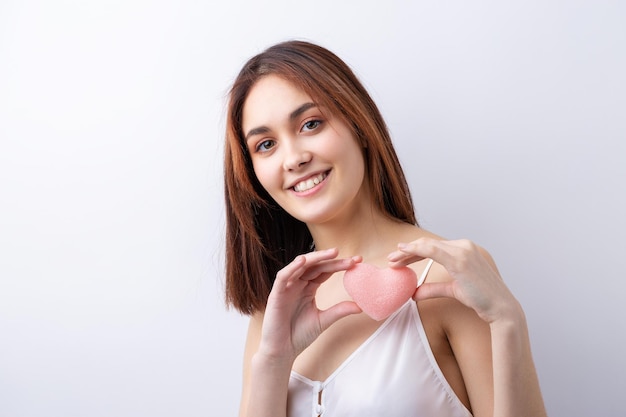 Belle femme souriante avec un maquillage naturel de peau propre et des dents blanches sur fond gris