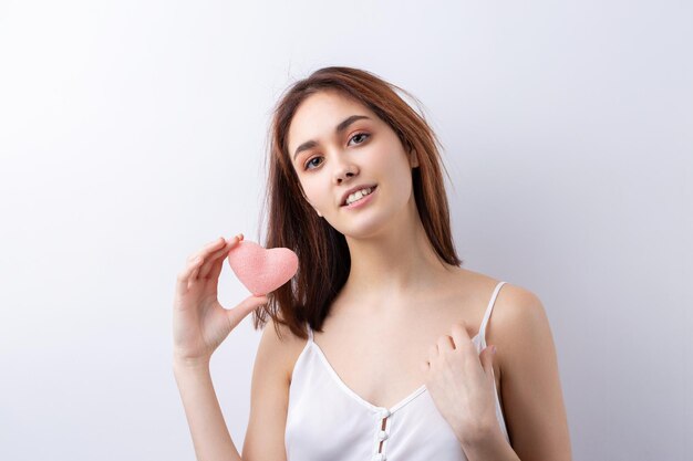 Belle femme souriante avec un maquillage naturel de peau propre et des dents blanches sur fond gris