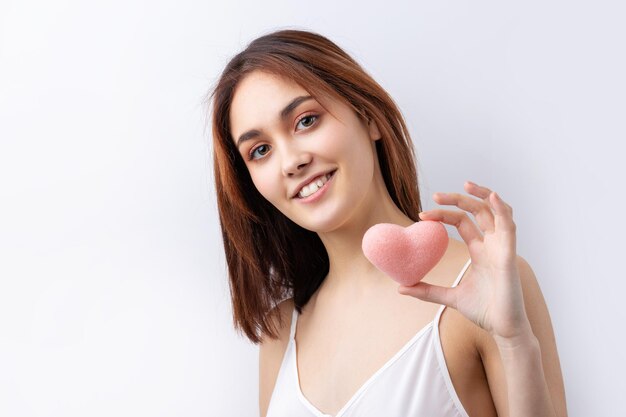 Belle femme souriante avec un maquillage naturel de peau propre et des dents blanches sur fond gris