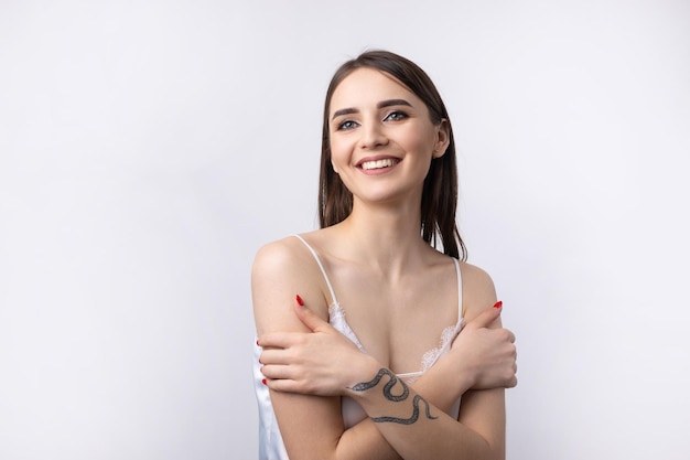 Belle femme souriante avec un maquillage naturel de peau propre et des dents blanches sur fond gris