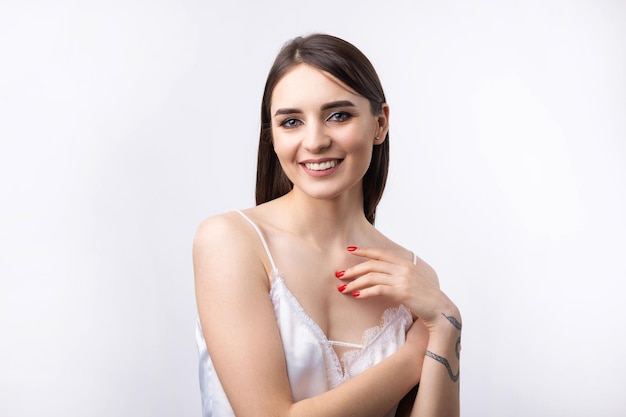 Belle femme souriante avec un maquillage naturel de peau propre et des dents blanches sur fond gris