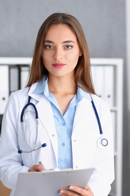 Belle femme souriante médecin debout au bureau