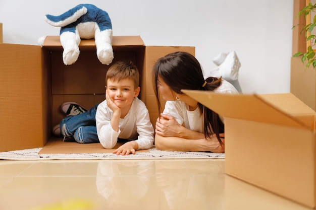 Belle femme souriante et petit garçon avec des boîtes en carton déménageant dans une nouvelle maison