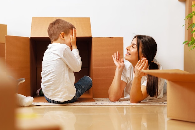 Belle femme souriante et petit garçon avec des boîtes en carton déménageant dans une nouvelle maison