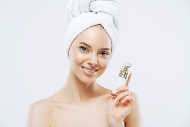 Belle femme souriante pose avec un produit cosmétique