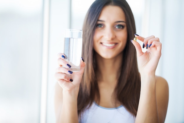 Belle femme souriante prenant des pilules de vitamines