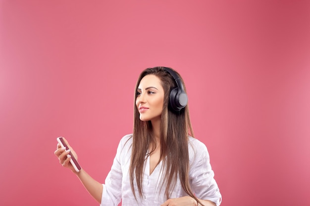 Belle femme souriante regardant de côté en écoutant sa musique préférée via un casque sans fil