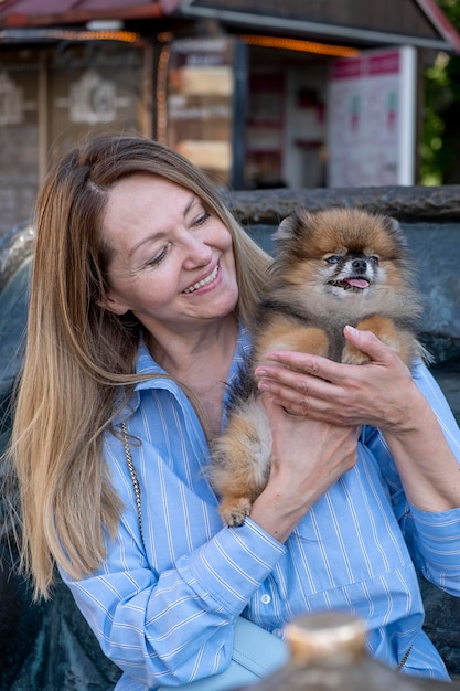 Belle femme souriante Senior étreignant son petit chien dans le parc