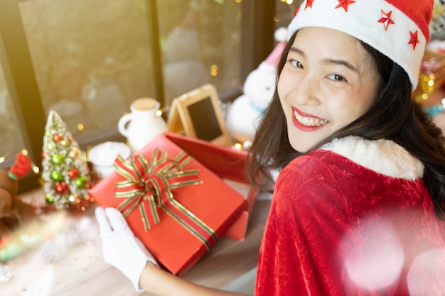 Belle femme souriante avec son coffret ouvert et accessoires de joyeux Noël décorés dans la chambre.