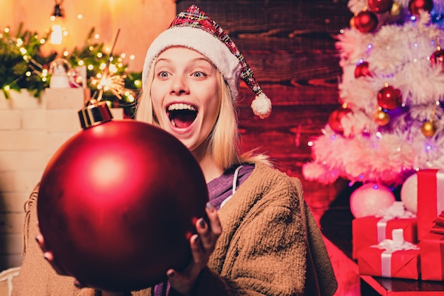 Belle femme souriante souhaite un joyeux Noël. Femme d'hiver portant un bonnet de Noel rouge. Vacances d'hiver