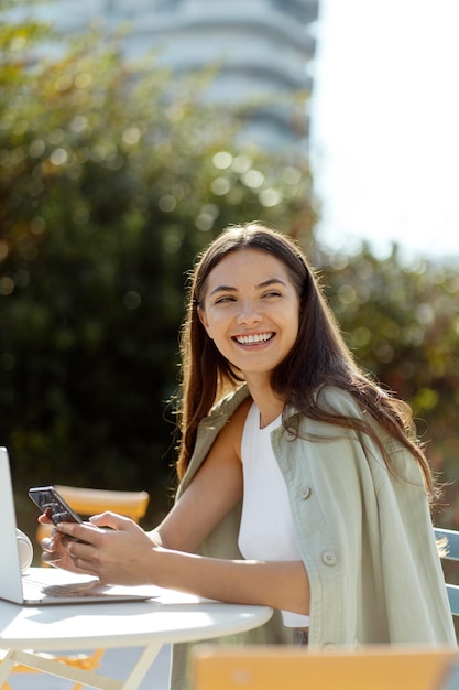 Belle femme souriante tenant un smartphone et faisant des achats en ligne sur l'application mobile