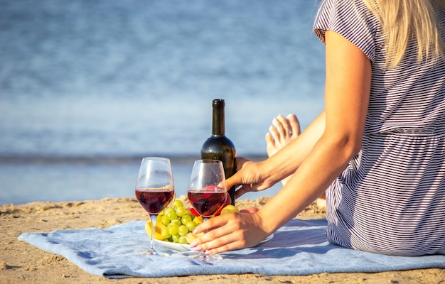 Belle femme souriante avec un verre de vin sur la plage. Vin rouge de fruits.