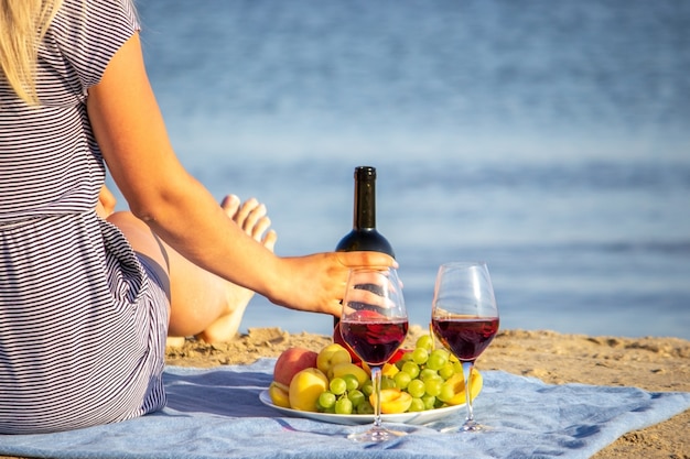 Belle femme souriante avec un verre de vin sur la plage. Vin rouge de fruits.