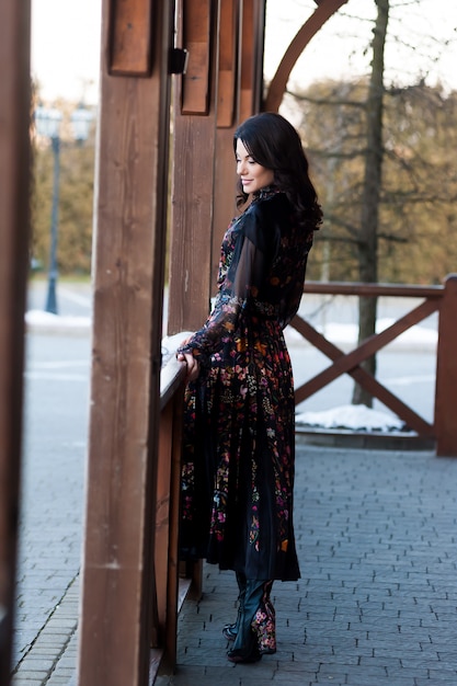 Belle femme avec sourire en robe près de main courante en bois