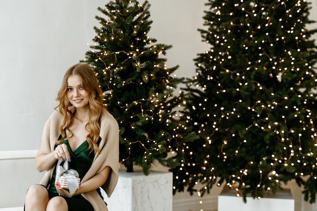 belle femme sourit dans le contexte d'un arbre de Noël à la maison