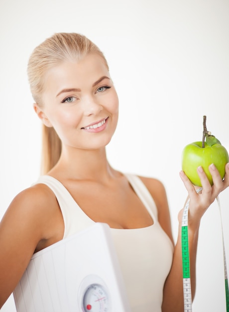 belle femme sportive avec échelle, pomme verte et ruban à mesurer