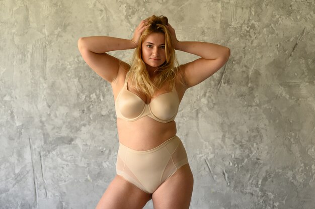 Belle femme en surpoids en maillot de bain beige sur fond gris