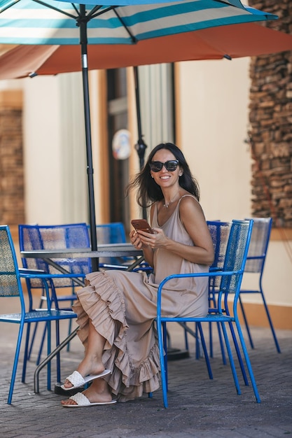 Une belle femme tape un message dans un café d'été en plein air.