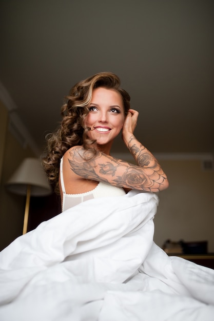 Photo belle femme avec tatouage souriant au lit.