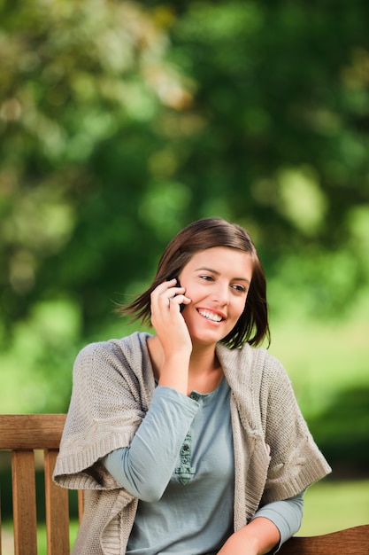 Belle femme téléphonant sur le banc