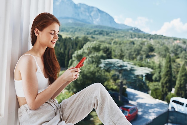 Belle femme avec un téléphone rouge terrasse extérieure luxe paysage loisirs vue sur la montagne