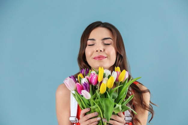 Belle femme tenant un bouquet de tulipes sur un fond de couleur