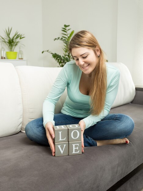 Belle femme tenant des briques en bois avec des lettres faisant le mot amour