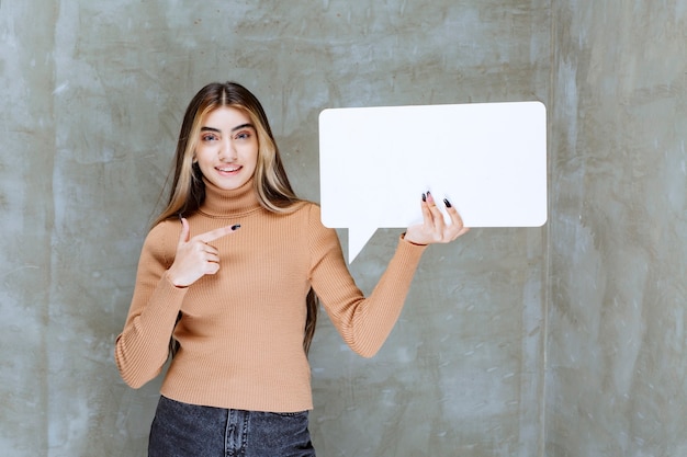 Belle femme tenant une bulle de dialogue vide sur un mur de pierre