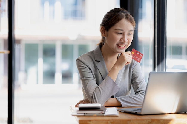 Belle femme tenant une carte de crédit, elle utilise une carte de crédit pour payer des biens et des services en ligne le concept d'utilisation d'une carte de crédit pour les achats en ligne en commandant des biens et des services sur le site Web