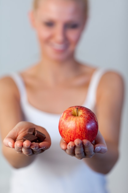 Belle femme tenant le chocolat et la pomme se concentrent sur la pomme