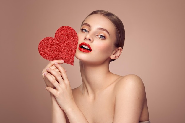 Une belle femme tenant un cœur rouge artificiel