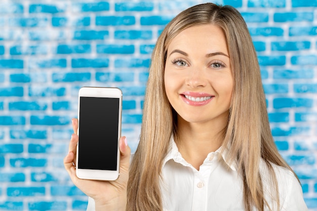 Belle femme tenant et montrant un téléphone mobile blanc avec écran noir blanc