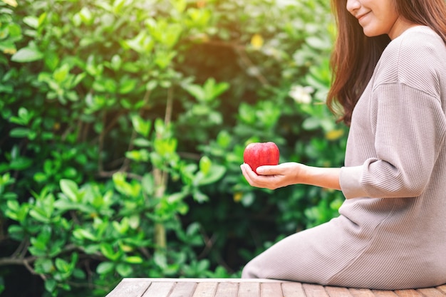 Une belle femme tenant une pomme rouge fraîche à manger